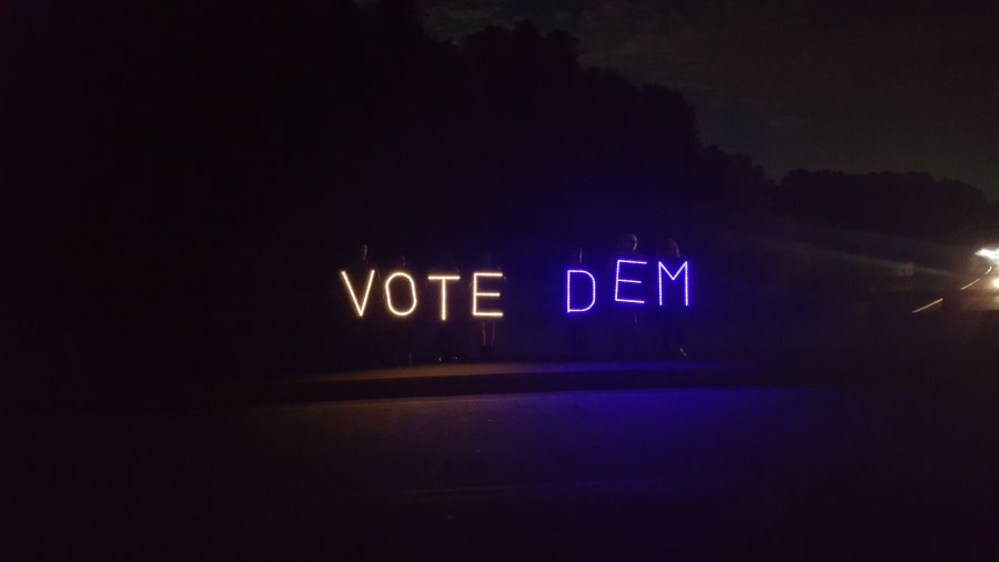 volunteers holding lighted letters saying VOTE DEM on an overpass