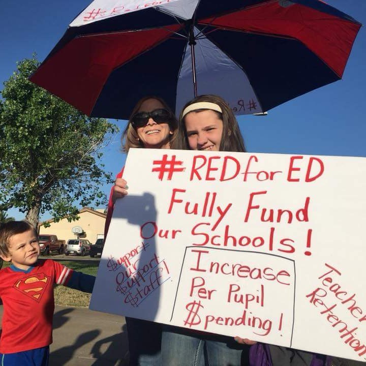 family with a protest sign saying Red for Ed Fully Fund Our Schools